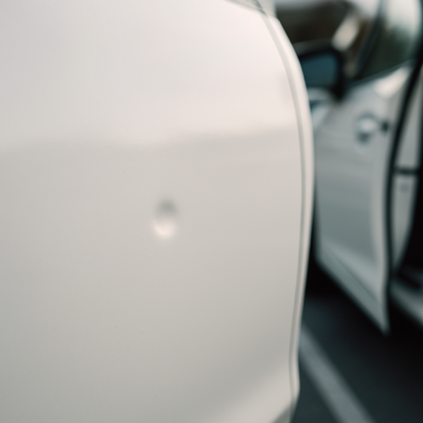 Door ding on a white car door in a parking lot - Sacramento door ding repair guide